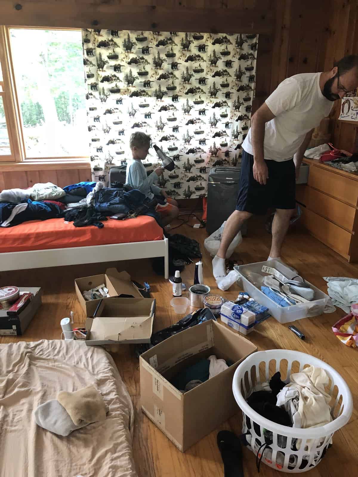 a very messy room inside our house with us packing belongings for the boat.
