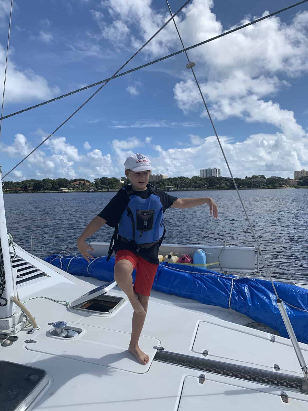 a boy balancing on one foot, on a catamaran