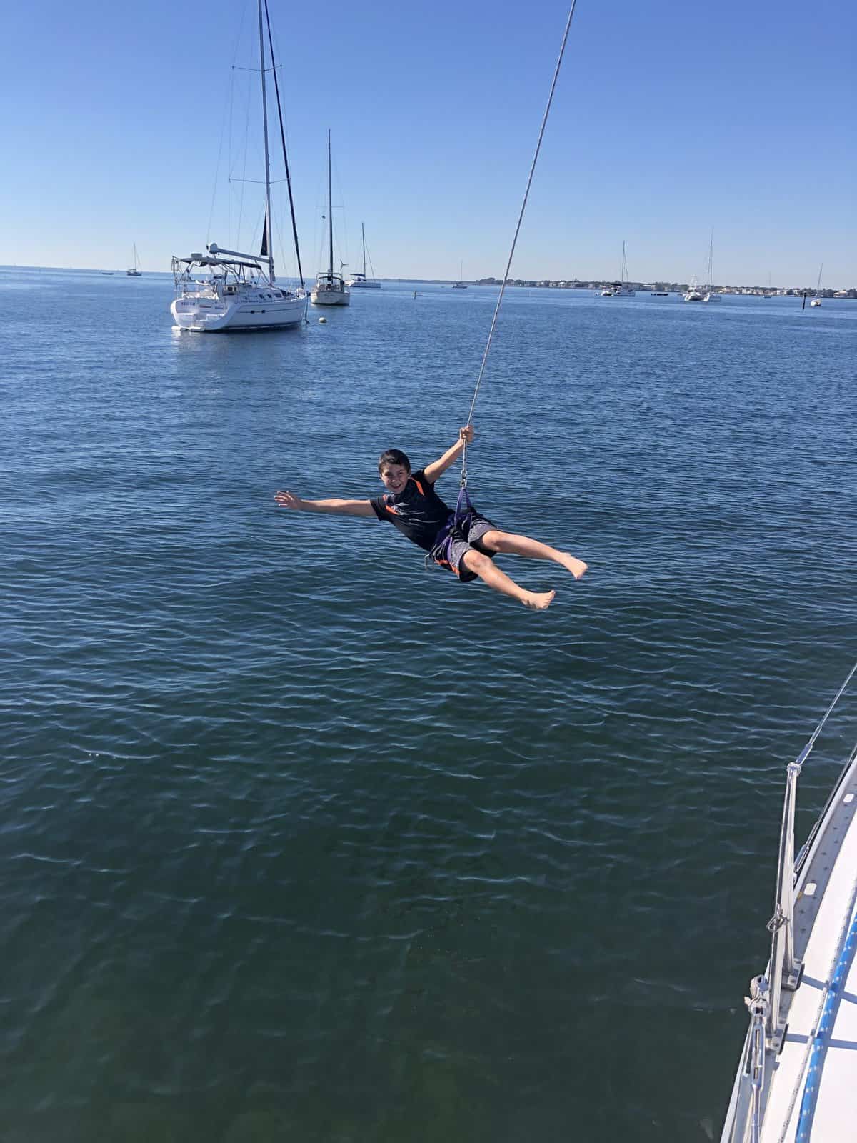 a boy in a harness, swinging on a boat