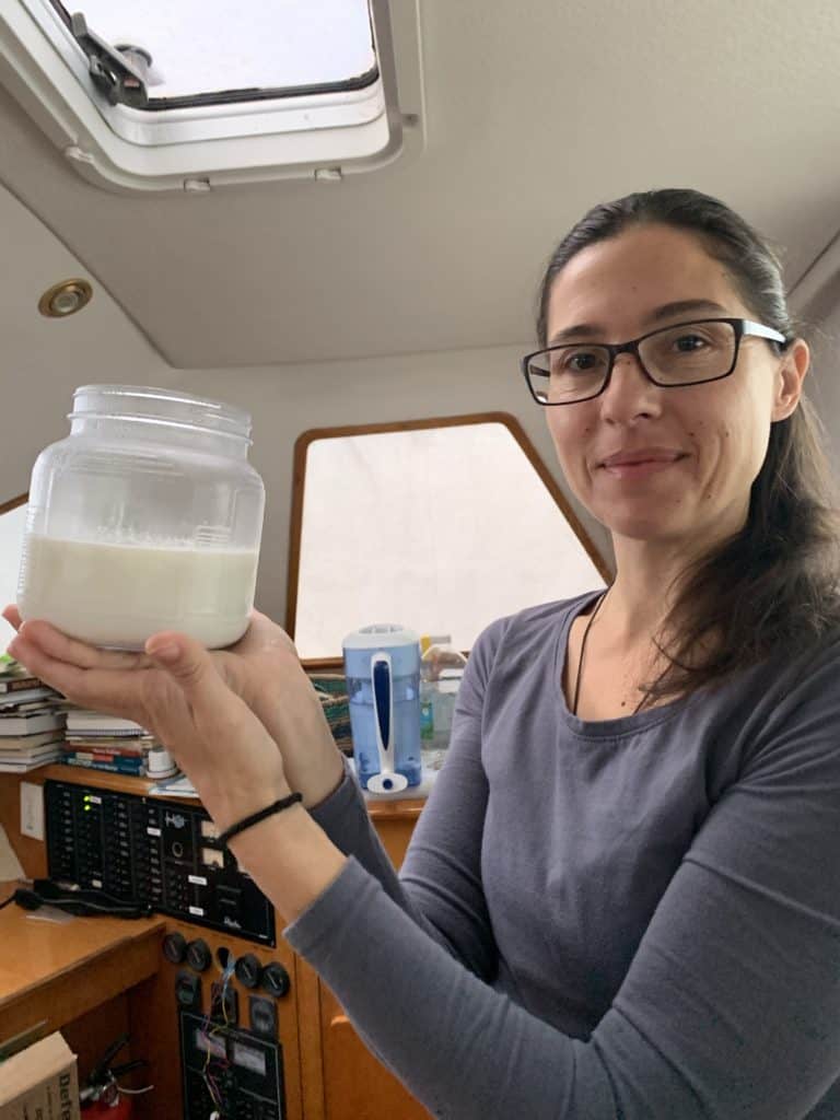 a woman holding a yoghurt jar on a boat