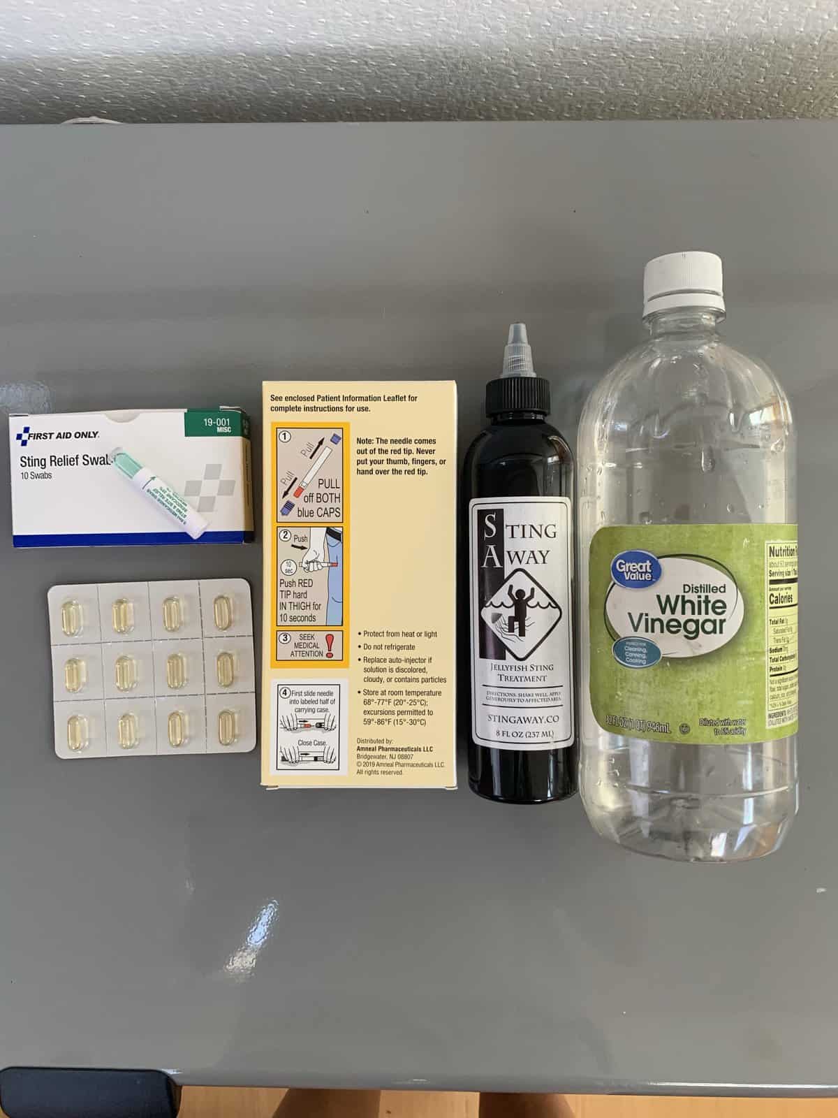 a display of anti-allergy supplies - sting relief, white vinegar, Benadryl, an epi pen