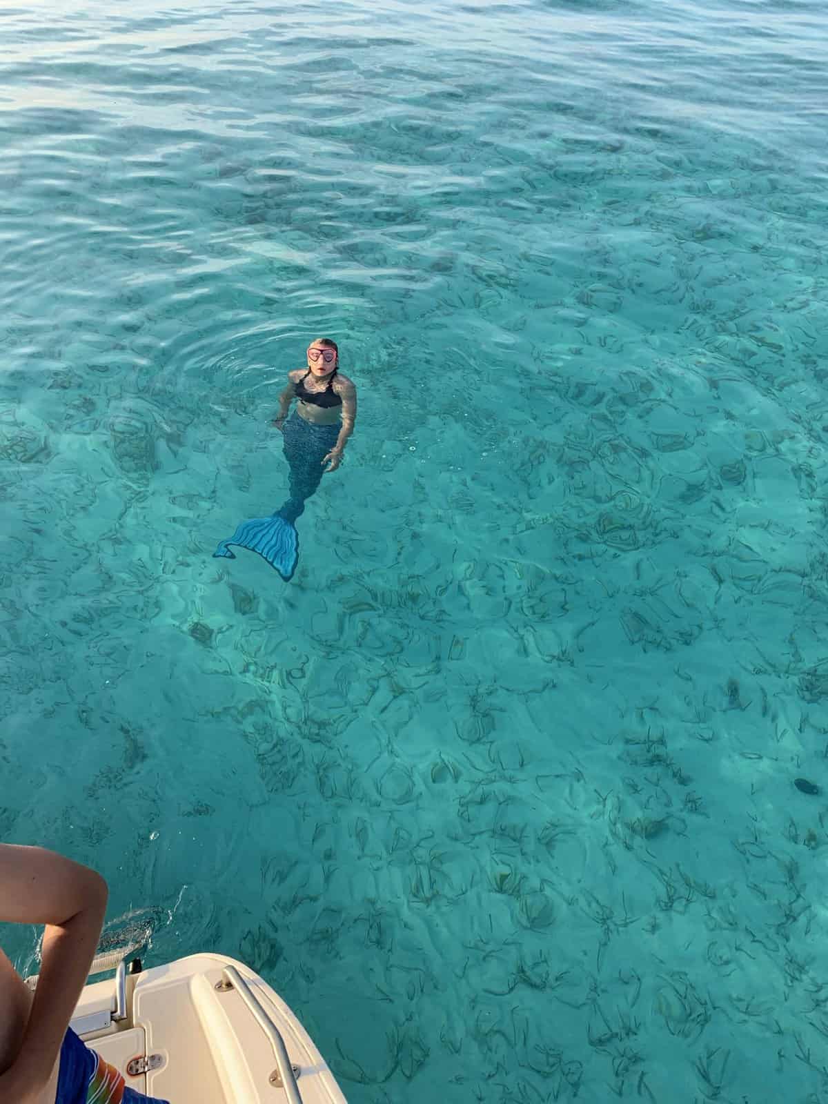 A girl with mermaid tail in crystal clear water