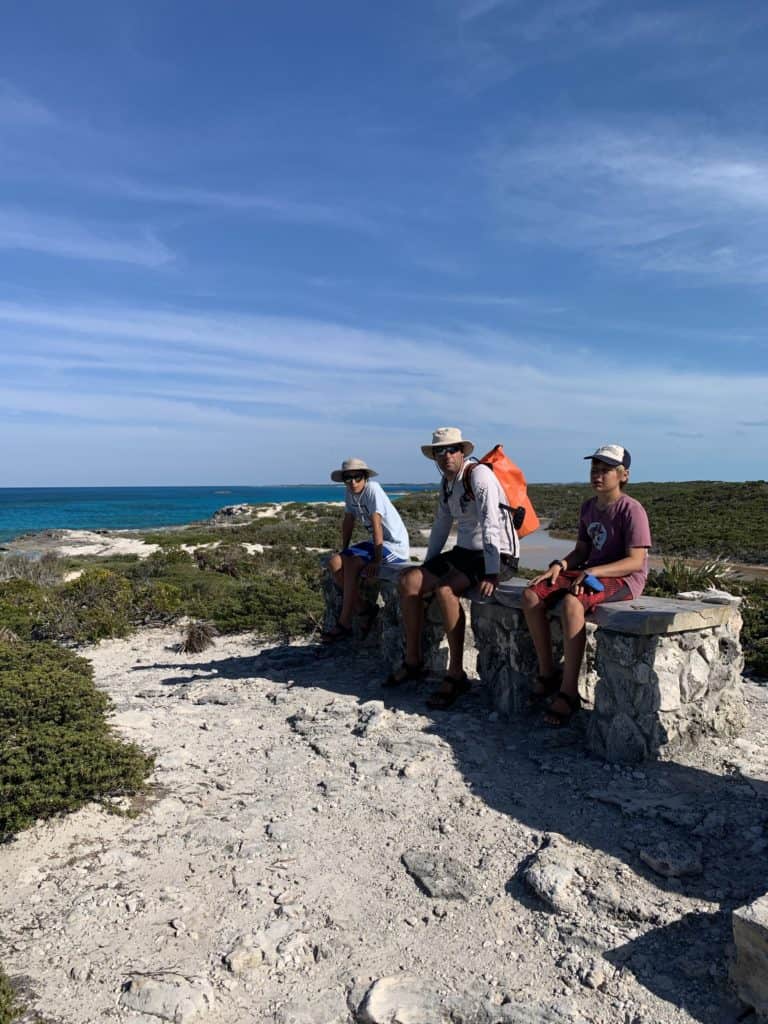 dad and two boys sitting on a rock in the Bahamas Land and Sea Park
