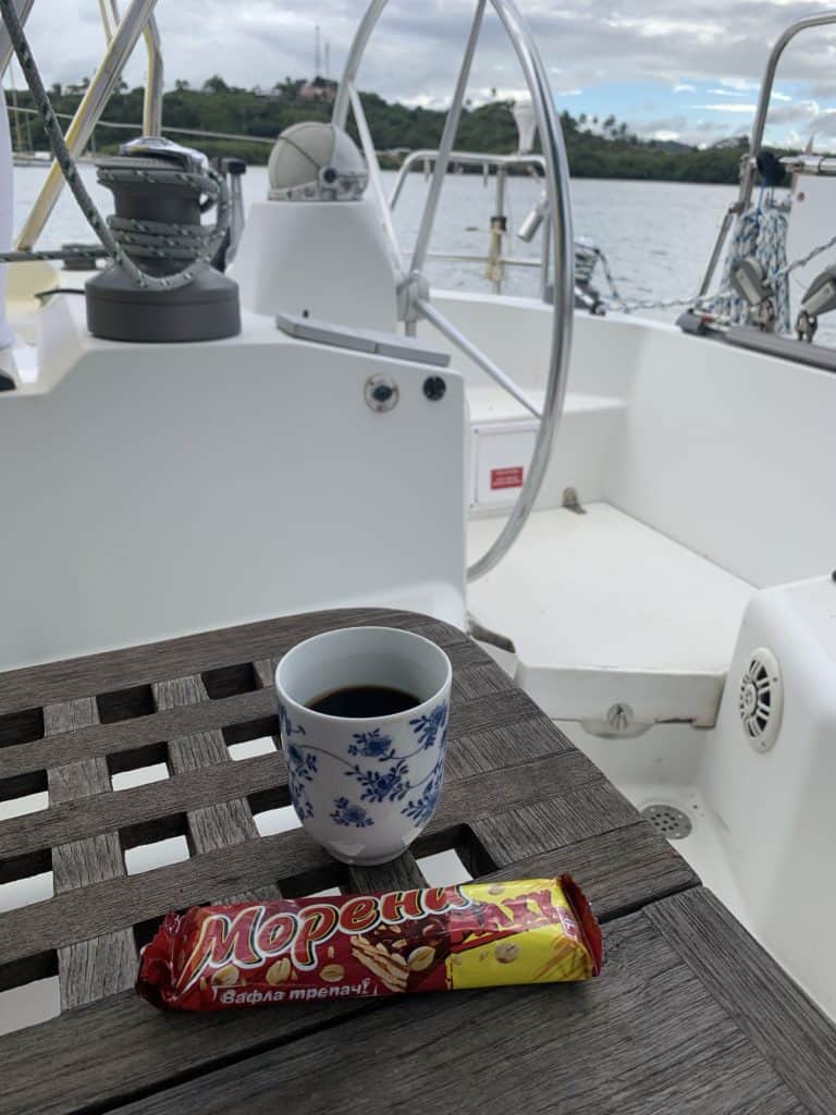 a cup of coffee and a wafer aboard a sailboat