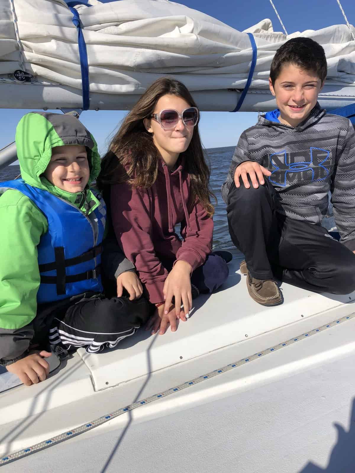 three younger kids on a boat, in jackets