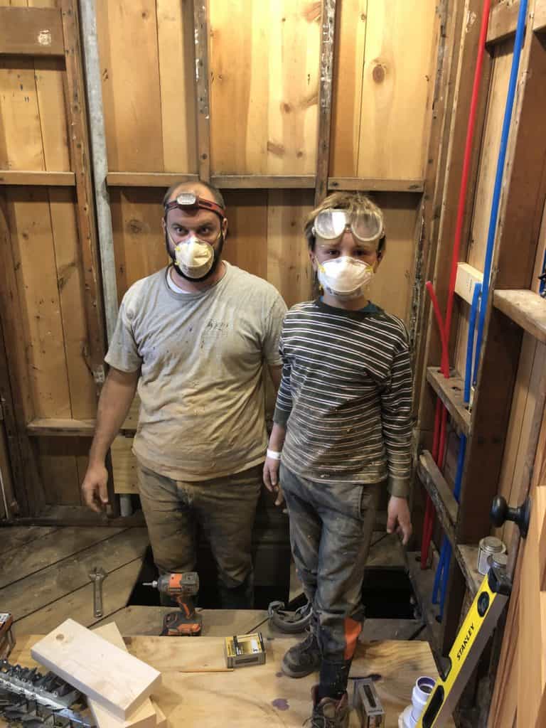 father and a son with respirators on, in a dusty hole.