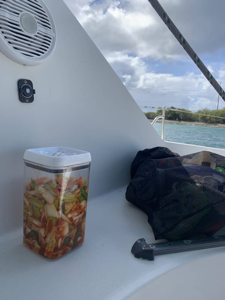 kimchi stored in a plastic container in the cockpit of a boat