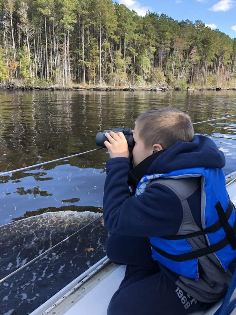 a boy watching with bird binoculars from a sailboat