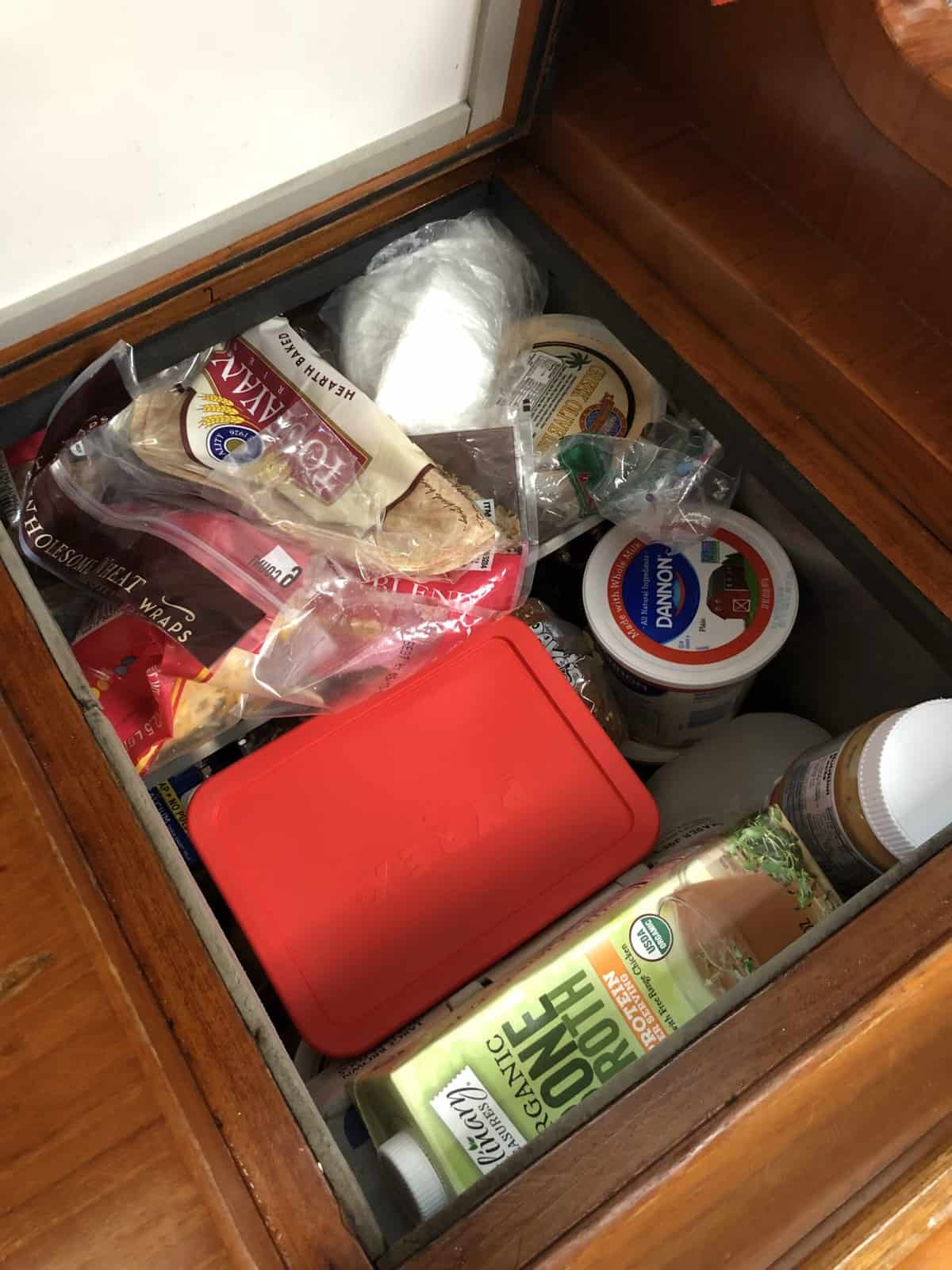 drop down fridge on a boat, filled with organized food