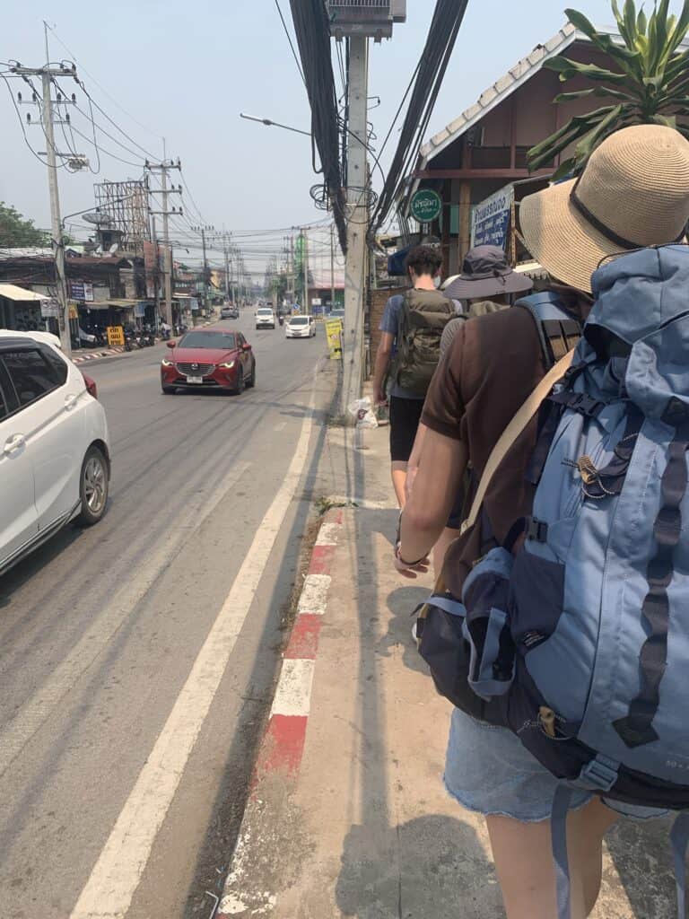 people walking on the sidewalk with backpacks on