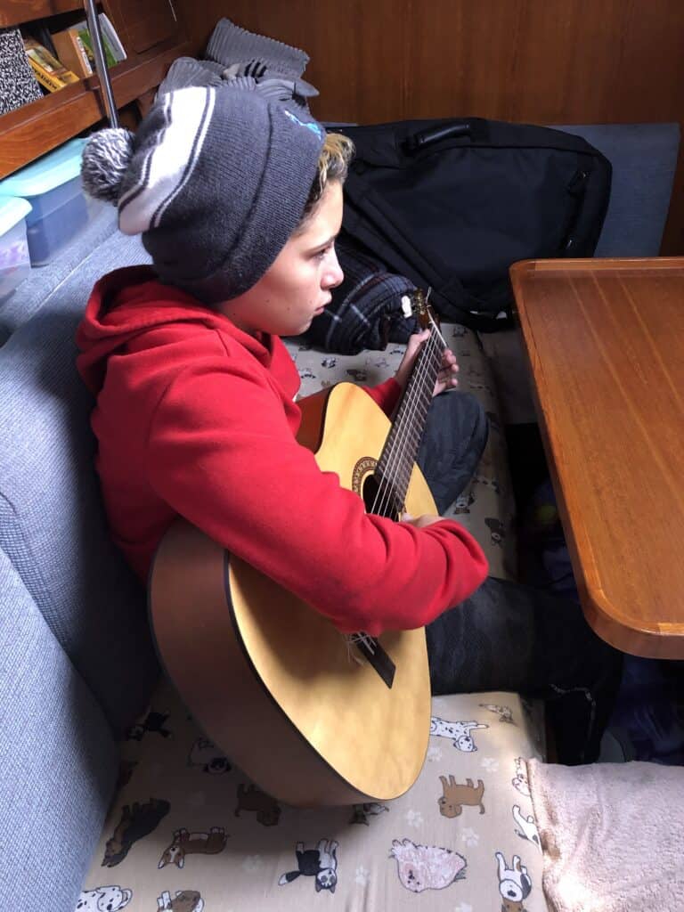 a boy playing a guitar in the cockpit of a boat