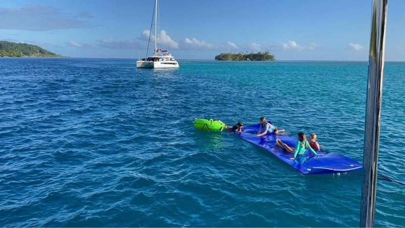a swim platform next to a catamaran in a tropical water sea