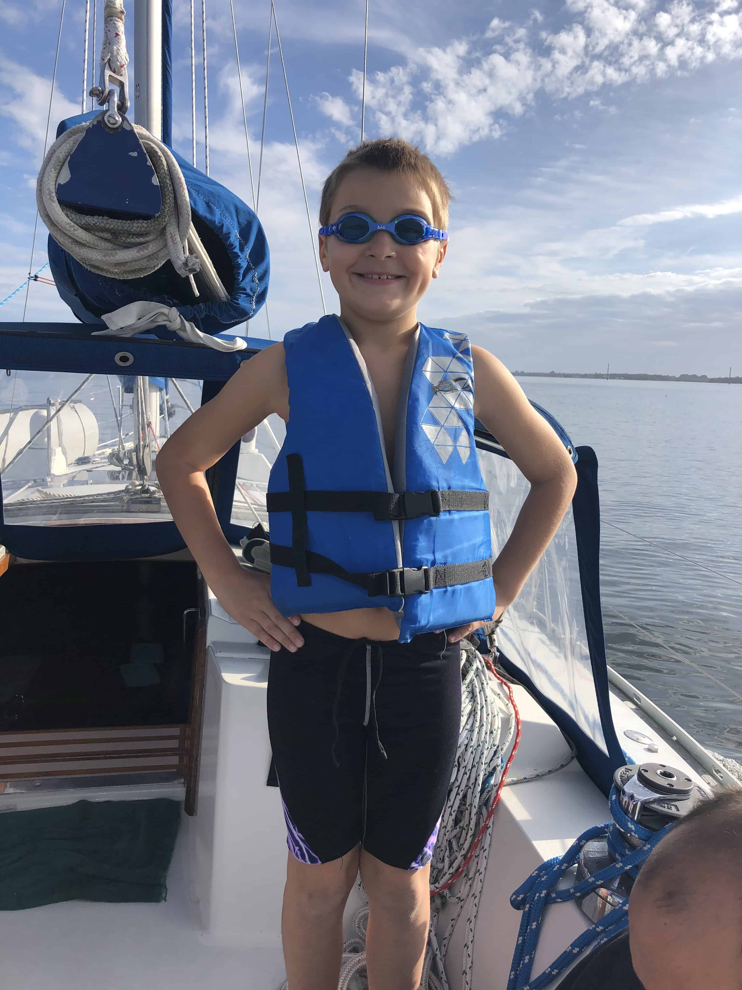 a boy on a sailboat wearing a life jacket