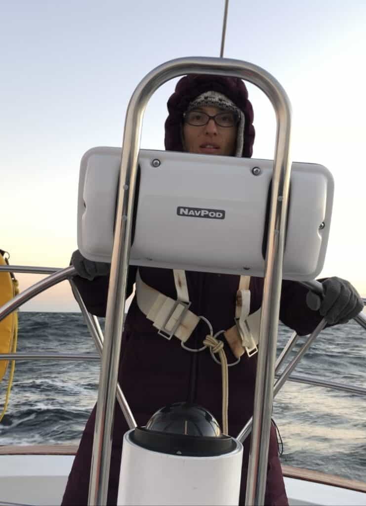 a woman wearing a jacket, hat and harness on a sailboat