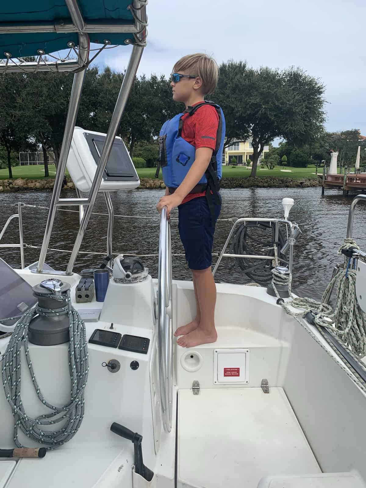 a child at the helm of a sailboat wearing no shoes