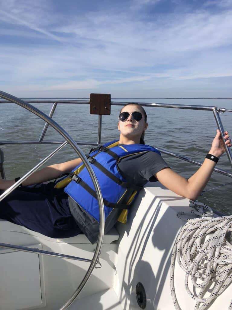 a girl wearing a life jacket on a sailboat