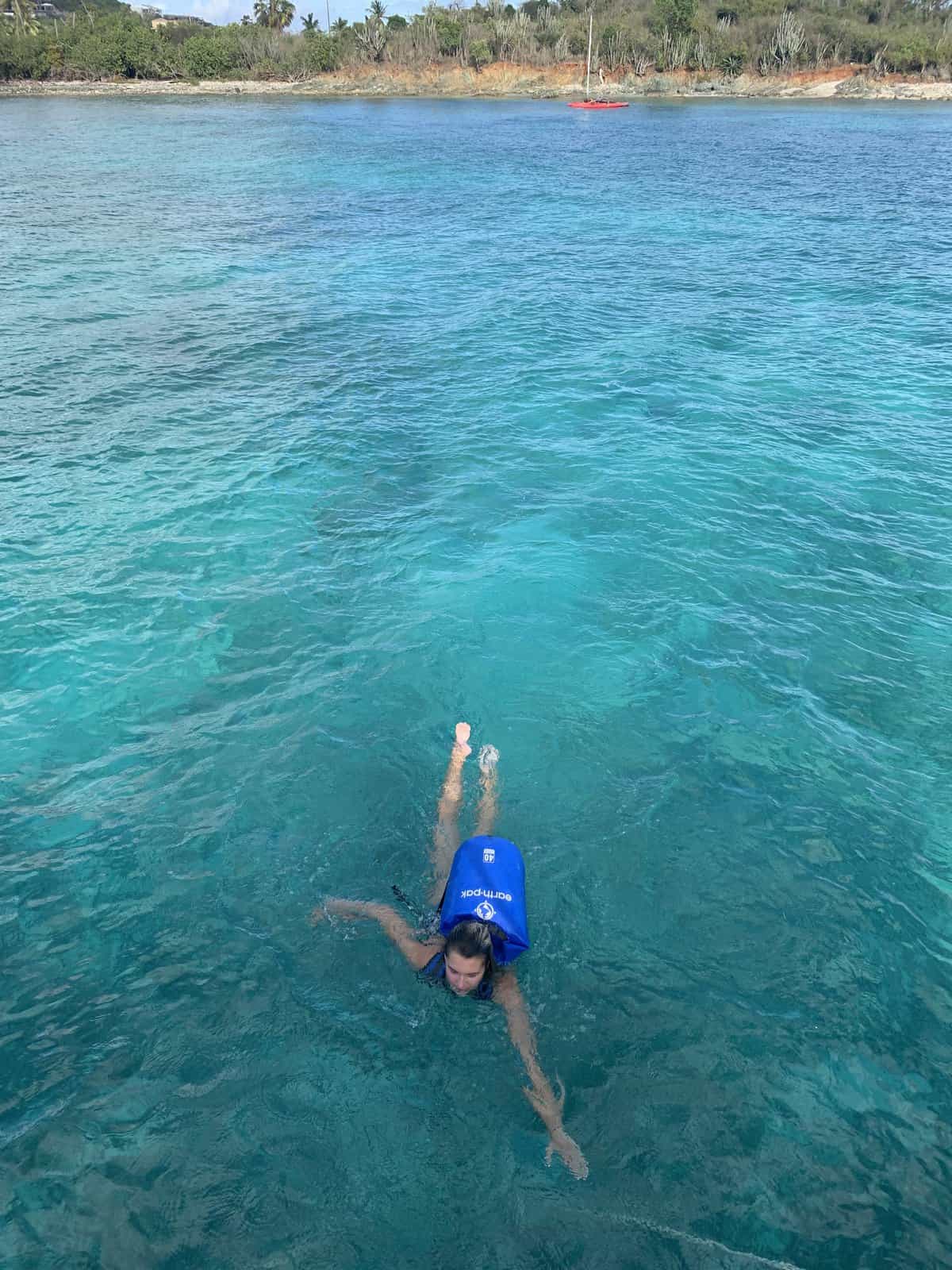 a girl swimming with a dry bag on